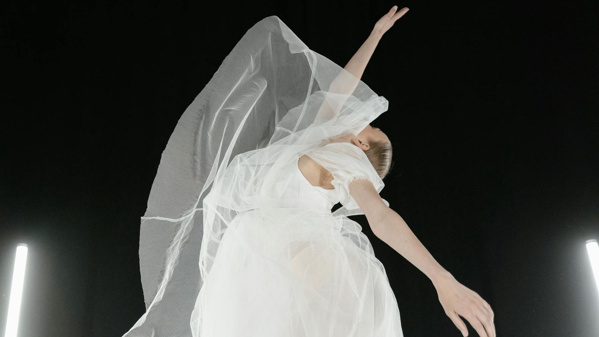Woman performing elegant movements in a bright airy studio space.